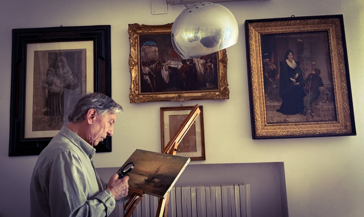 Professor Mimmo Dattoli examining a painting with a magnifier lens, surrounded by old masters